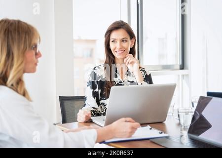 Group of businesswoman using laptops while sitting at table and working together. Teamwork. Stock Photo