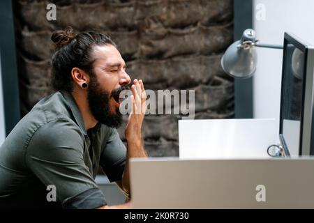 Tired exhausted man, office worker, manager or freelancer, working in office Stock Photo