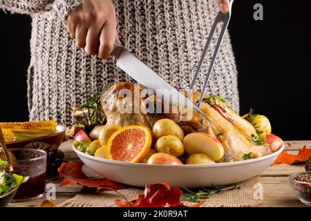 Close up of caucasian woman carving thanksgiving roast turkey with vegetables Stock Photo