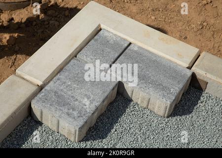 Laying gray concrete paving slabs in the courtyard of the house on a sandy foundation. Stock Photo