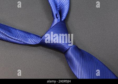 Blue tie with a classic knot on a gray background. Stock Photo