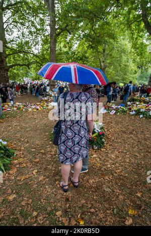 London UK. 13 September 2022. Despite the rain members of the public continue to bring flowers and personal messages of condolence to Green Park near Buckingham palace to express their sadness and sympathy after the death of Queen Elizabeth II the longest serving British monarch who died at Balmoral castle on 8 September. Millions of visitors are expected to descend on London to view the coffin of Her Majesty Queen Elizabeth who will be lying in state at Westminster Hall for four days until the sate funeral on Monday 19 September Credit: amer ghazzal/Alamy Live News Stock Photo
