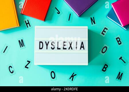 Dyslexia awareness, help children with reading, learning difficulties concept. Lightbox with DYSLEXIA word. Colorful books and different letters on Stock Photo