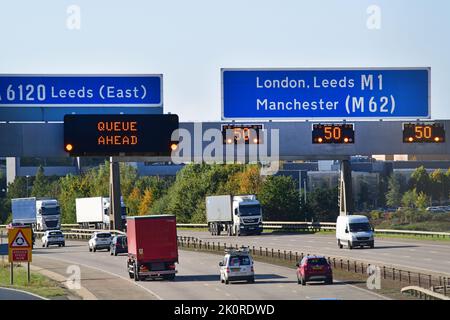 traffic passing flashing warning sign of 50mph reduced speed limit  on M1 motorway leeds united kingdom Stock Photo