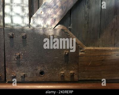 Vintage rusty iron plate bolted to old weathered wooden beams Stock Photo