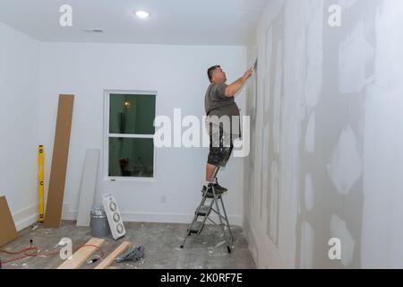 Worker trowels putty on drywall finishing putty with hand a spatula. Stock Photo