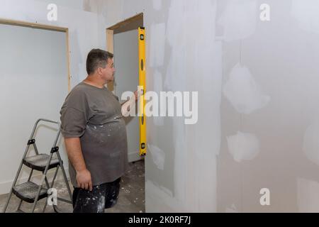 The employee checks the equality of a wall of drywall before painting Stock Photo