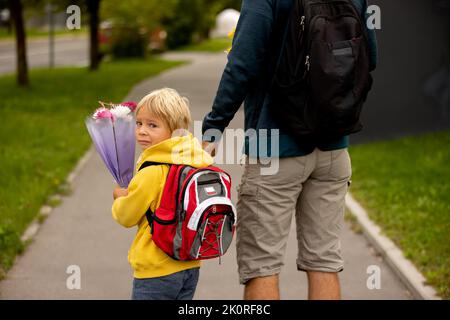 Sad little child,. holding fathers hand, going to school crying, caring bouquets of flowers for teachers, going to preschool Stock Photo