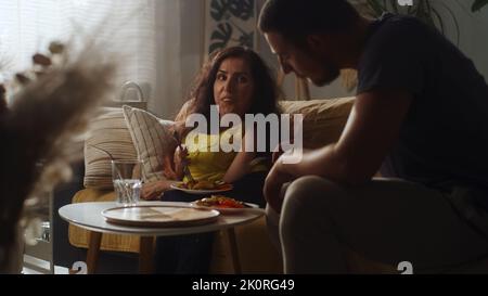 Woman with a physical disability and man joking and laughing together while sitting on a couch and having a dinner at home Stock Photo