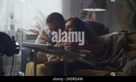 Man hugging his wife with a disability who sitting on a sofa and they talking and discussing drawing on digital tablet computer together at home Stock Photo
