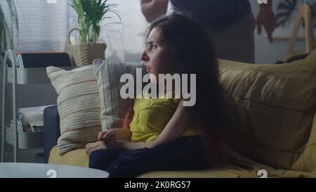 Confused woman with a disability sitting on a couch and talking with nervous man while they arguing and having quarrel Stock Photo
