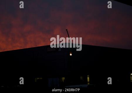 Fiery sunset over industrial silhouette. Angled horizon. Stock Photo