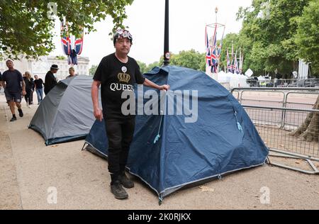London, UK. 13th Sep, 2022. John Loughrey from London stands next to his tent on the street 'The Mall' in front of Buckingham Palace. Britain's Queen Elizabeth II died on Sept. 8, 2022, at the age of 96. On September 14, her coffin will be transferred in a public procession across the Mall from Buckingham Palace to Westminster Hall. Credit: Christian Charisius/dpa/Alamy Live News Stock Photo