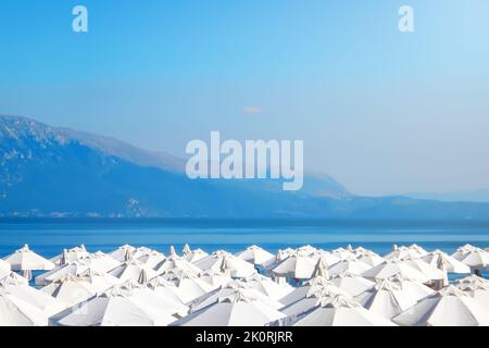 Overcrowded beach, white umbrellas against the sea, Summer time Stock Photo
