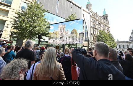 Crowds gather at screens outside Belfast City Hall to watch a Service of Reflection for Queen Elizabeth II at nearby St Anne's Cathedral. attended by King Charles III and the Queen Consort during their visit to Northern Ireland. Picture date: Tuesday September 13, 2022. Stock Photo