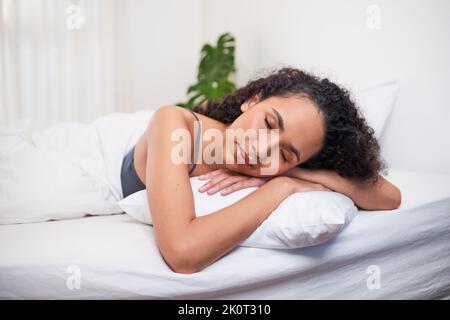 A young multi-ethnic woman sleeps in bed comfortably on her stomach Stock Photo