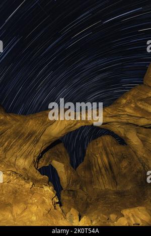 Star trails over Double Arch at night with artificial light painting with a hand-held spotlight.  Arches National Park, Moab, Utah. Stock Photo