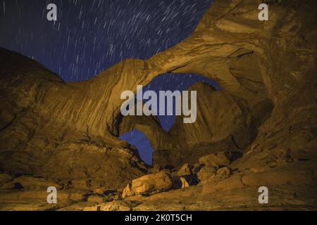 Short star trails over Double Arch at night with artificial light painting with a hand-held spotlight.  Arches National Park, Moab, Utah. Stock Photo