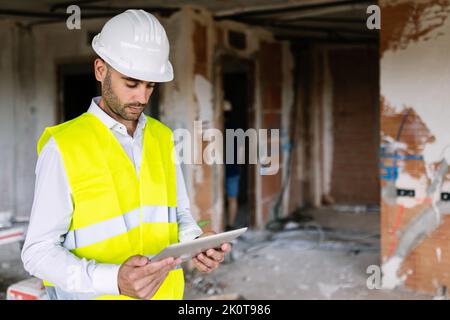Young adult man architect at construction site working on digital tablet Stock Photo