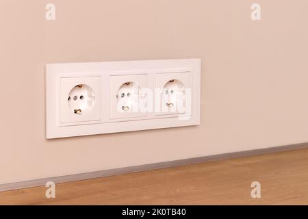 Group of white european electrical outlets on modern beige wall. Selective focus Stock Photo