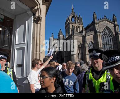 Royal Mile, Edinburgh, Scotland, UK. Crowds gather for Coffin of Her Majesty Queen Elizabeth II departing St Giles Cathedral. 13th September 2022. Pictured: One young man holds up a piece of paper as a protest, believed to be blank as police officers and pedestrians pass. Credit: Arch White/alamy live news.