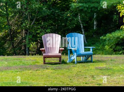 Colourful chairs at a park with trees in the background. Stock Photo