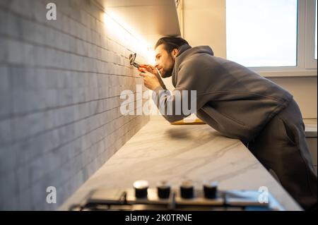 Electrician installing the power outlet on the kitchen wal Stock Photo
