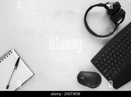 Computer keyboard, wireless mouse, headphones, notebook, pen. Workplace desk, workspace flat lay with copy space. Office work or working from home. Stock Photo