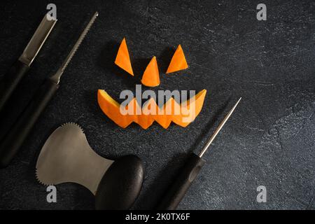 Halloween pumpkin pieces. Carved Jack Lantern eyes, nose, mouth. Jack-o'-lantern elements and carving tools. Spoon, saw blade, pointed or grove carver Stock Photo