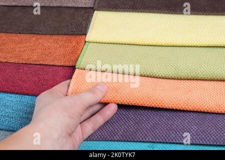 Woman chooses samples of colored fabric on table close up Stock Photo