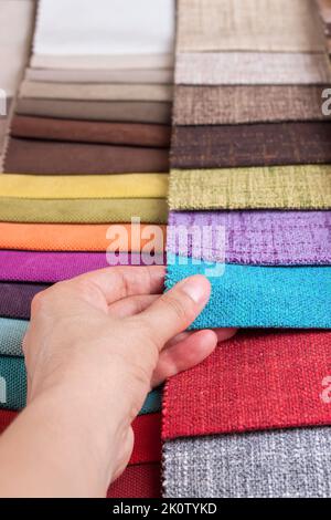 Woman hand chooses samples of colored fabric on table close up Stock Photo