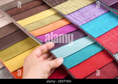 Woman hand chooses samples of colored fabric on table close up Stock Photo