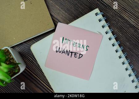 Concept of Interns Wanted write on sticky notes isolated on Wooden Table. Stock Photo