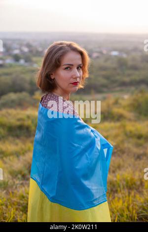 Sad Woman in long dress holding a yellow and blue flag of Ukraine Stock Photo