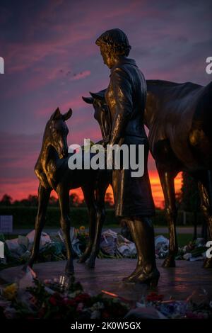 Newmarket, Suffolk, UK. 13th September, 2022. The Queen's statue on Birdcage Walk Newmarket becomes a shrine as people pay their respects. Sunsets on Tuesday evening. Picture by Credit: Mark Westley/Alamy Live News Stock Photo