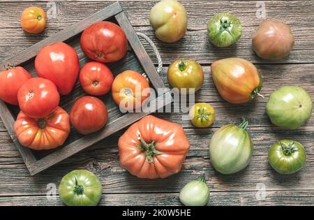 Organic multicolored untreated tomatoes on a wooden table, top view Stock Photo