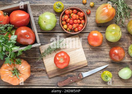 Multicolored untreated tomatoes on a wooden table, top view Stock Photo