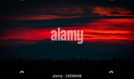 Red cloudy dark sunset near Jested hill over Liberec town in summer evening Stock Photo