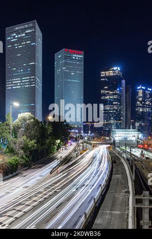 long exposure of cars in the city with buildings in the background at night. busy highway beneath office buildings. Stock Photo