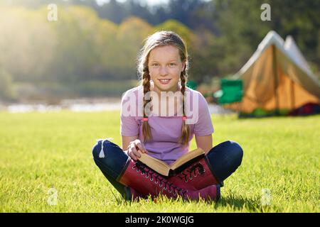 Books are better than anything. a teenage girl relaxing with a book on the grass. Stock Photo