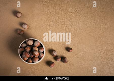 Pile of hazelnuts filbert in a bowl on a brown background. Fresh nuts in their shells. Stock Photo