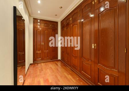 Dressing room of an apartment with large closets with reddish wood doors, mirrors and wooden floors Stock Photo