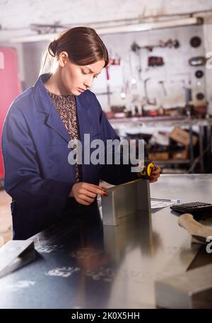 Woman working with metal and using measuring tape Stock Photo