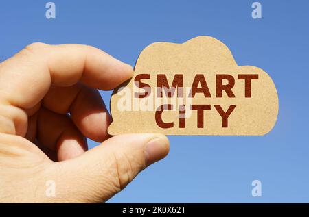 Against the background of the sky in the hands of a man, a figure of a cloud with the inscription - Smart city. Technology and business concept. Stock Photo