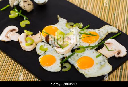 Fried quail eggs with champignons Stock Photo