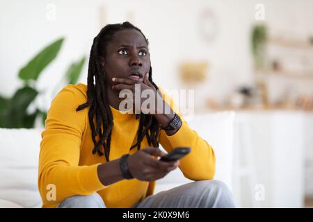 Portrait Of Shocked Black Man With Remote Controller In Hand At Home Stock Photo