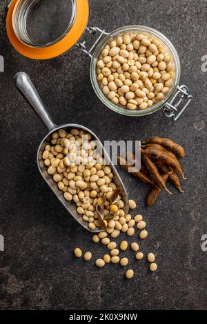 Soy beans. Dried soybean pod in scoop on the black table. Top view. Stock Photo