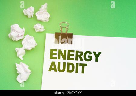 Ecology concept. On a green background, crumpled paper and a sheet with the inscription - Energy Audit Stock Photo
