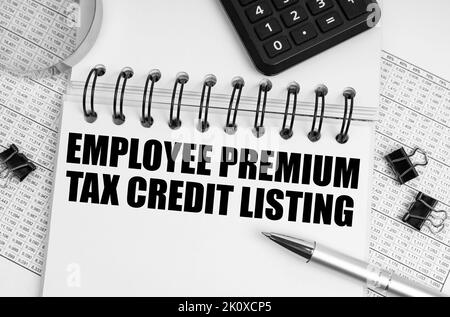 Business and finance concept. On the table is a magnifying glass, a calculator and a notebook with the inscription - Employee Premium Tax Credit Listi Stock Photo