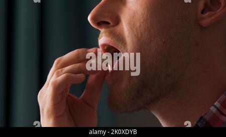 A young man watches a movie and eats roasted corn while sitting in the living room on the couch in his home  Stock Photo